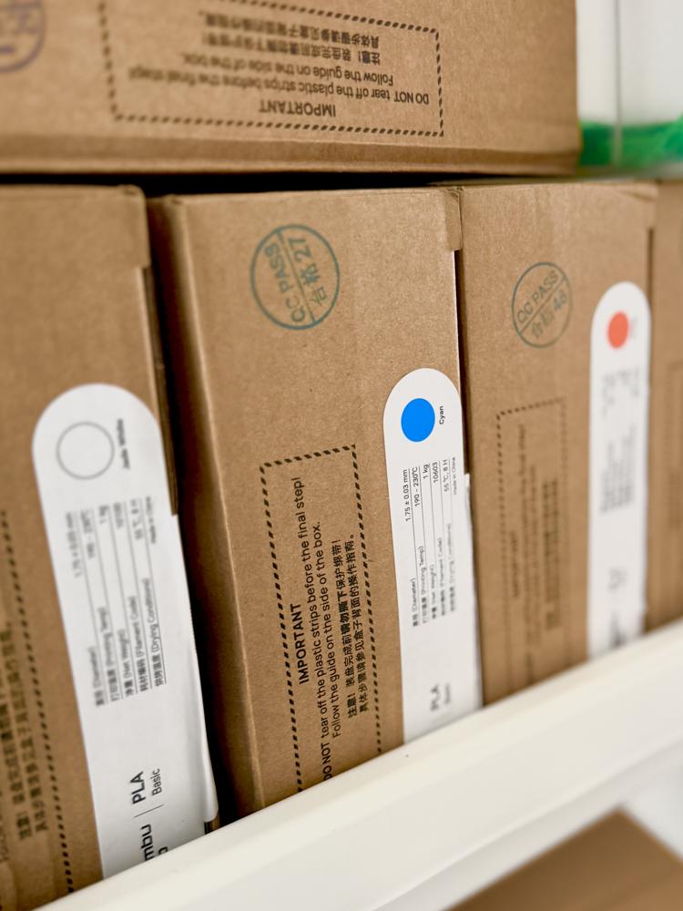 Scatole di bobine di filamento PLA con etichette colore bianco, ciano e rosso